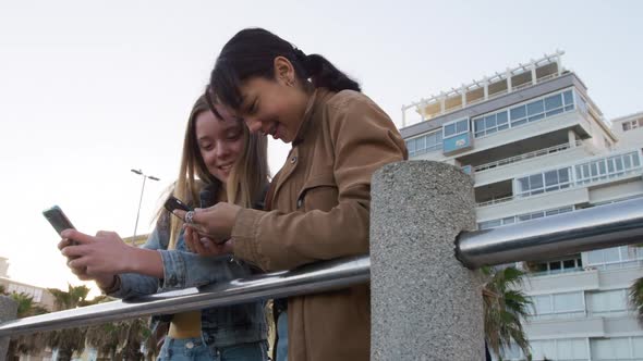 Low angle of a Caucasian and a mixed race girl using their phones