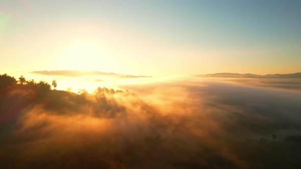 4K aerial view over a misty mountainous area. The great golden sun in the morning