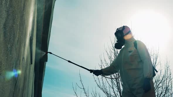 Worker Uses Sprayer While Disinfecting a Building