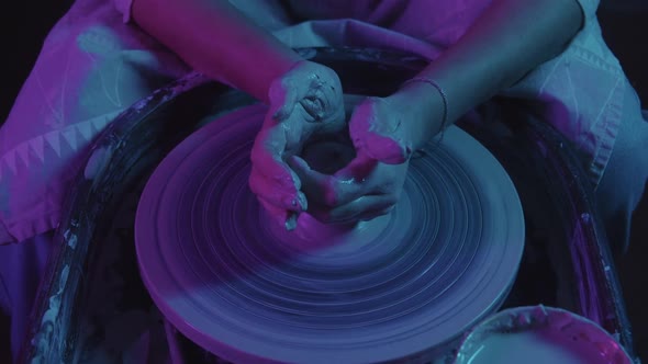 Pottery Workshop  Female Hands Pulling the Clay in Oblong Shape  Neon Lighting