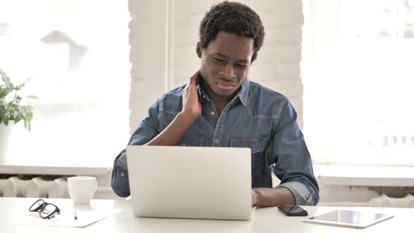 Tired African Man with Neck Pain Working on Laptop