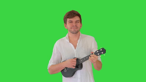 Young Man Playing Ukulele While Walking on a Green Screen, Chroma Key.