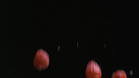 Throwing Up and Falling Down Raspberries and Drops of Water on the Black Background in Slow Motion