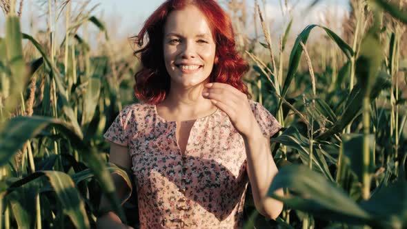 Cute Ginger Woman with Red Hair Walking on the Corn Field Looking at Camera