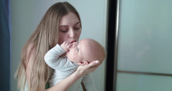 Happy Mother Holds Her Lovely Newborn Son Caresses Him and Rejoices in Room