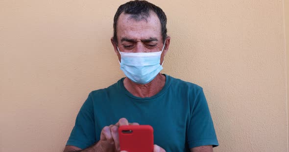 Senior man using mobile phone - Mature guy wearing face protective mask