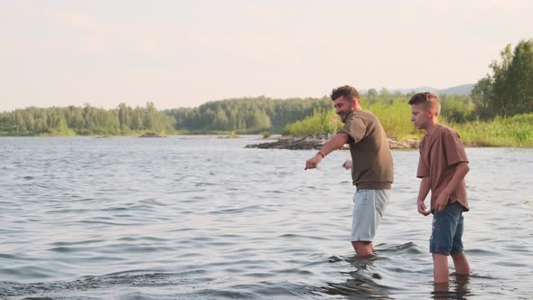 Man and Boy Throwing Rocks Standing in Lake