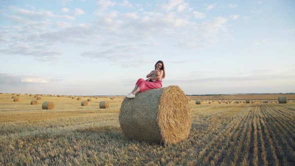 Beautiful Young Mother Lulling Her Baby Son with Smile When Relaxes on Haystack