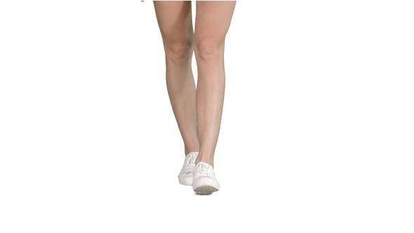 Female legs in white sneakers walking on white background.