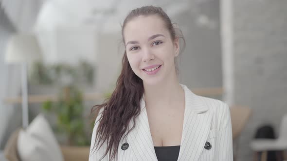 Portrait Cute Businesswoman Standing in a Light Comfortable Office Looking at the Camera. Successful