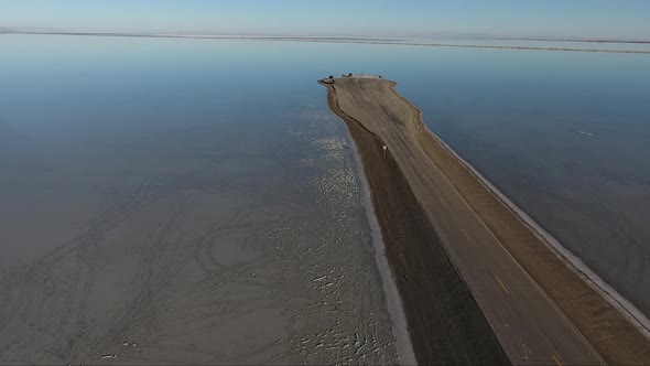 A drone shot flying over the Bonneville Salt Flats shows the Salt Flats causeway dividing the floode