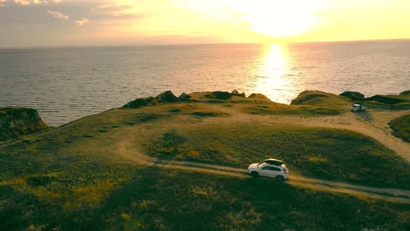 Scenic Hilly Coastline with Suv on Dirty Road with Dramatic Marine Sunset on Background