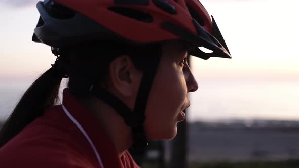 CloseUp of Focused Motivated Confident Face of Female Cycling Sportsman in Red Protective Helmet