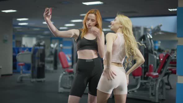 Young Slim Caucasian Millennial Women Taking Selfie in Gym Smiling and Posing