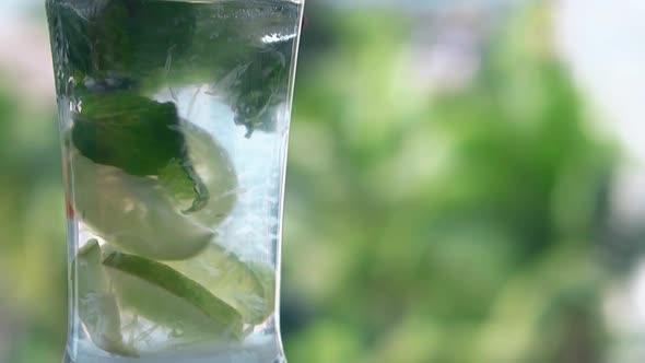 Red Plastic Straw Moves Slowly in Shining Glass with Mojito