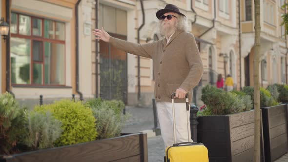 Confident Senior Male Tourist with Travel Bag Hitchhiking on Town Street. Portrait of Elegant Old