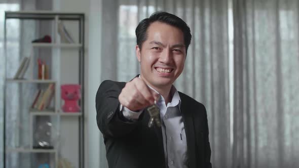 Close Up Of Asian Real Estate Agent Smiling And Showing Keys To Camera In The House For Sale