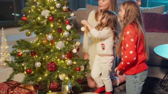 Mother with Daughters Decorating Christmas Tree at Home