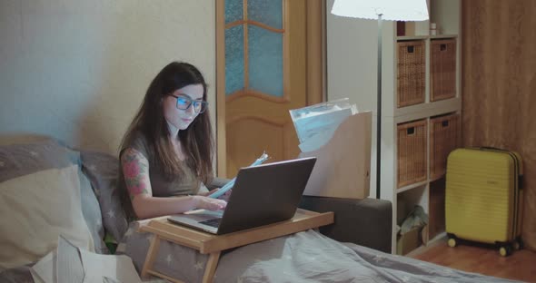 Pretty Asian Woman is Working on a Laptop in Bed on Self Isolation