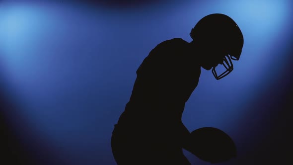 Silhouette of Determined Professional American Football Player in Helmet Isolated on Blue Background