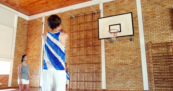 School students playing basketball in basketball court