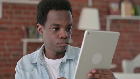 African Man Celebrating Success on Tablet