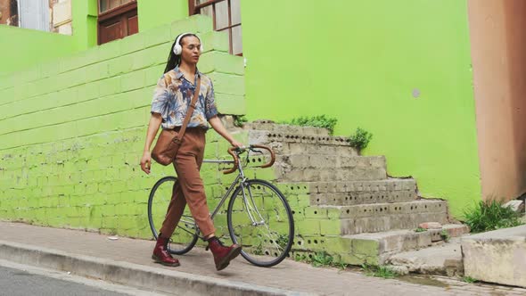 Mixed race man walking with a bike