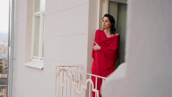 Woman in a Red Silk Robe Goes Out on a Balcony in Moscow on a High Floor