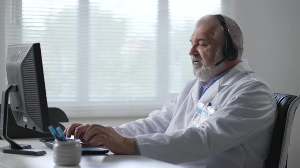 Male Doctor Sitting At The Table And Using Laptop