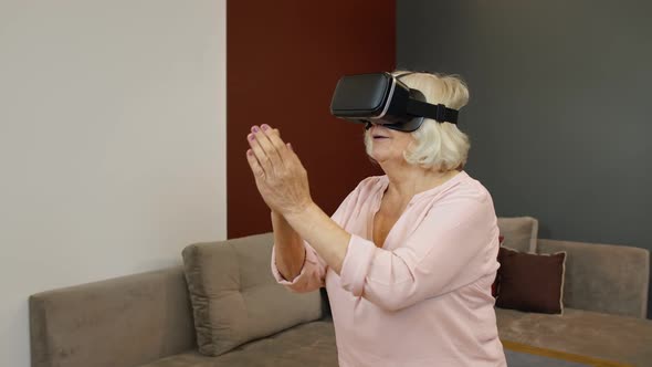 Senior Grandmother Woman in Virtual Headset Glasses Watching Amazing 3D Video in VR Helmet at Home