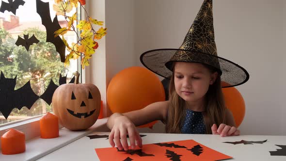 Preparation for Halloween Little Girl in Witch Costume Making Holiday Decoration Out of Black Bats
