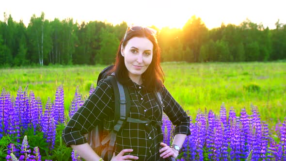 Portrait of Girl Hiker with Backpack in the Colors of the Sunset Looking at the Camera Lupine