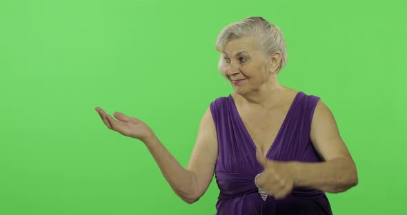 An Elderly Woman Points at Something and Smiles. Old Grandmother. Chroma Key