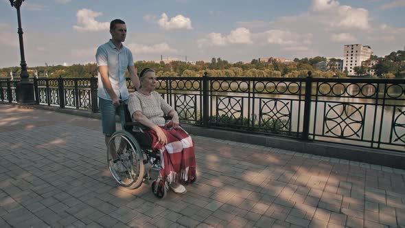 Man Pushing Old Woman on a Wheelchair