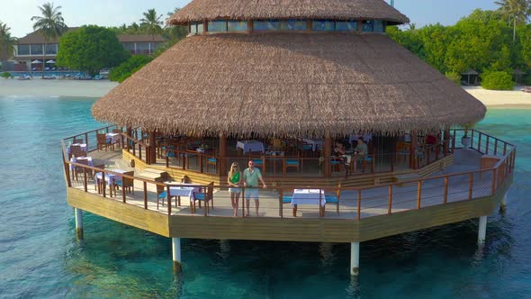 Aerial View on Young Couple in Water Restaurant on the Beach in Maldives Resort Island