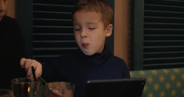 Boy in Cafe Eating Ice-cream and Watching Digital Tablet
