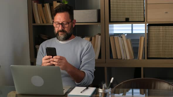 Businessman sitting office using smartphone and laptop