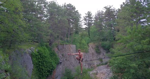 A man tries to balance while slacklining on a tightrope in the mountains