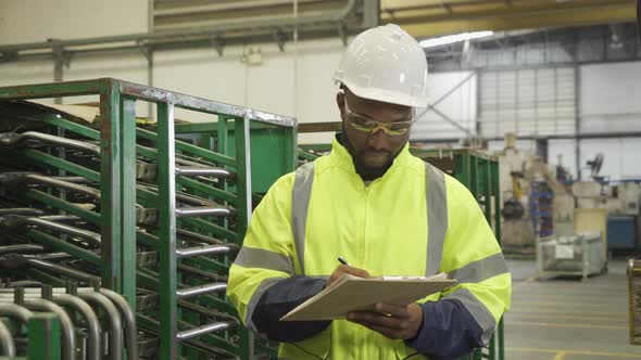 Portrait of Black African American man, an engineer or worker, with safety outfit checking quality