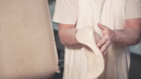 Chef Spinning and Stretching Pizza Dough in Kitchen