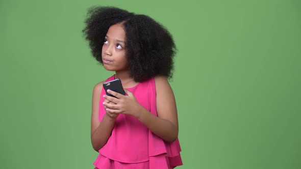 Young Cute African Girl with Afro Hair Using Phone and Thinking