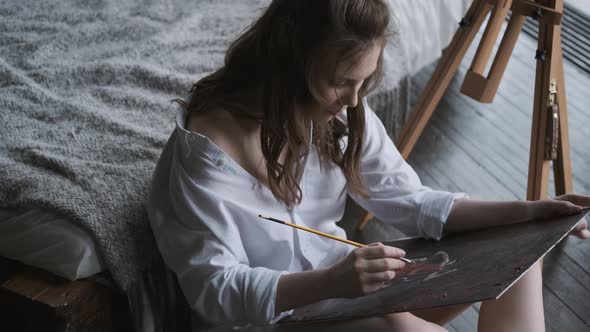 Portrait of a Girl Artist Working on a Painting in a Home Studio