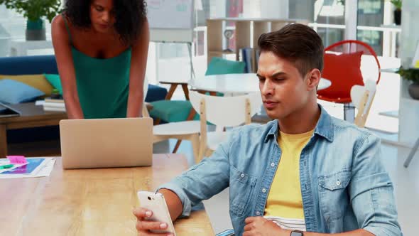 Male executive using mobile phone while colleague using laptop 4k