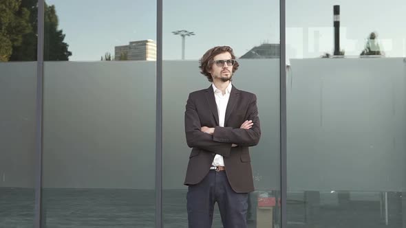 Businessman stands with his arms crossed near the business center