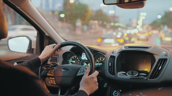 Man Driving Car Through the Streets of Evening City