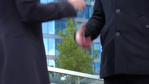 A Businessman and a Businesswoman Shake Hands and Talk, Then Walk Away Together - Closeup