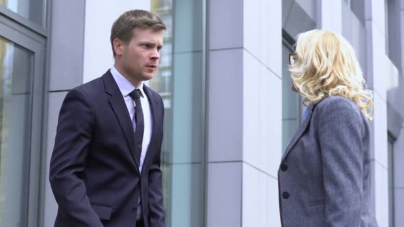 Young Man Catching Up With Elderly CEO on Street, Asking Help in Business