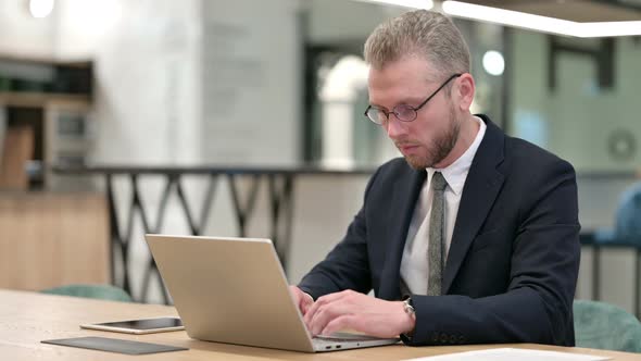 Focused Businessman Working on Laptop in Office 