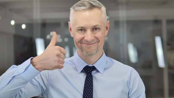 Thumbs Up By Grey Hair Businessman Looking at Camera