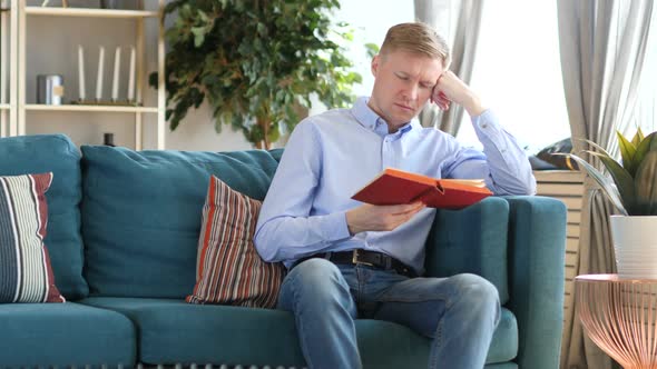 Sleeping Middle Aged Man Holding Book While Sitting on Sofa